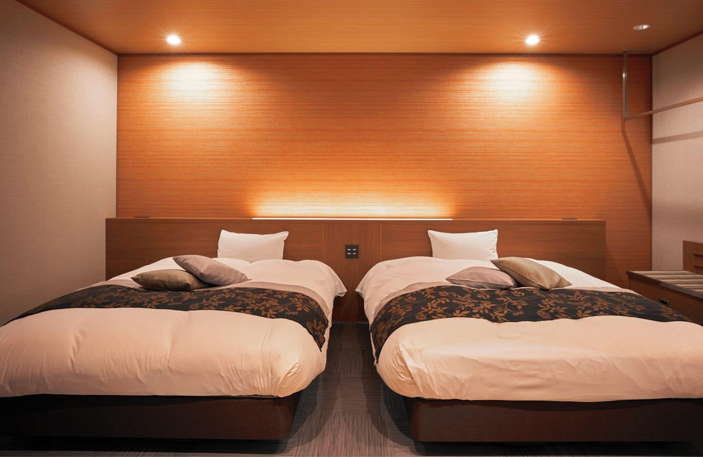 A hotel room with two beds, wooden headboard, and recessed lighting.