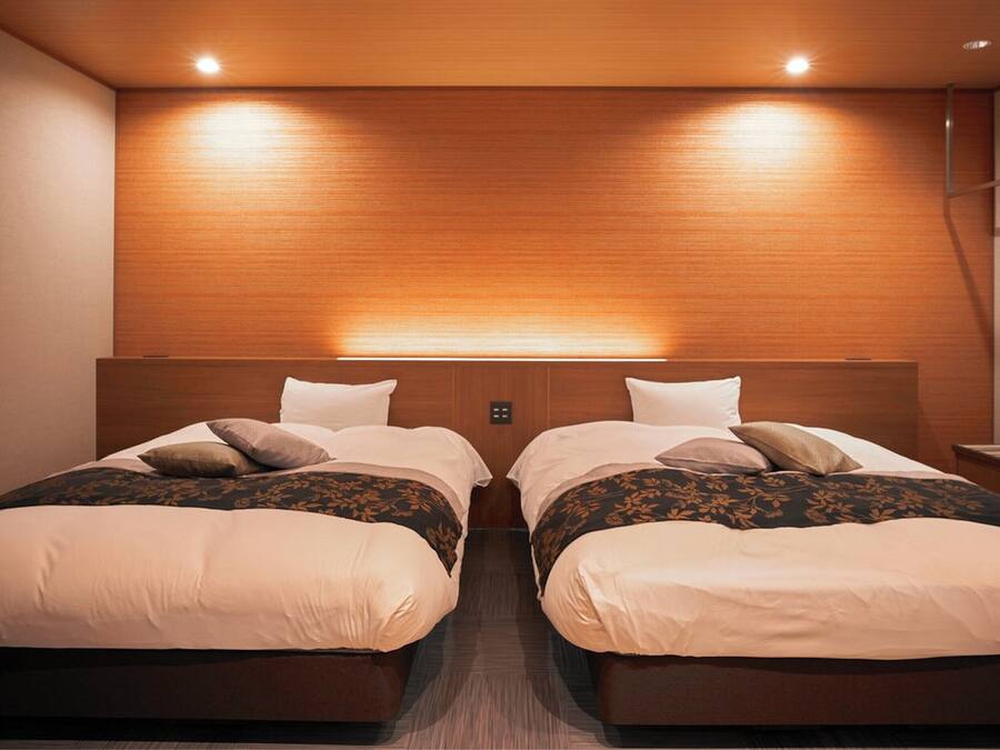A hotel room with two beds, wooden headboard, and recessed lighting.