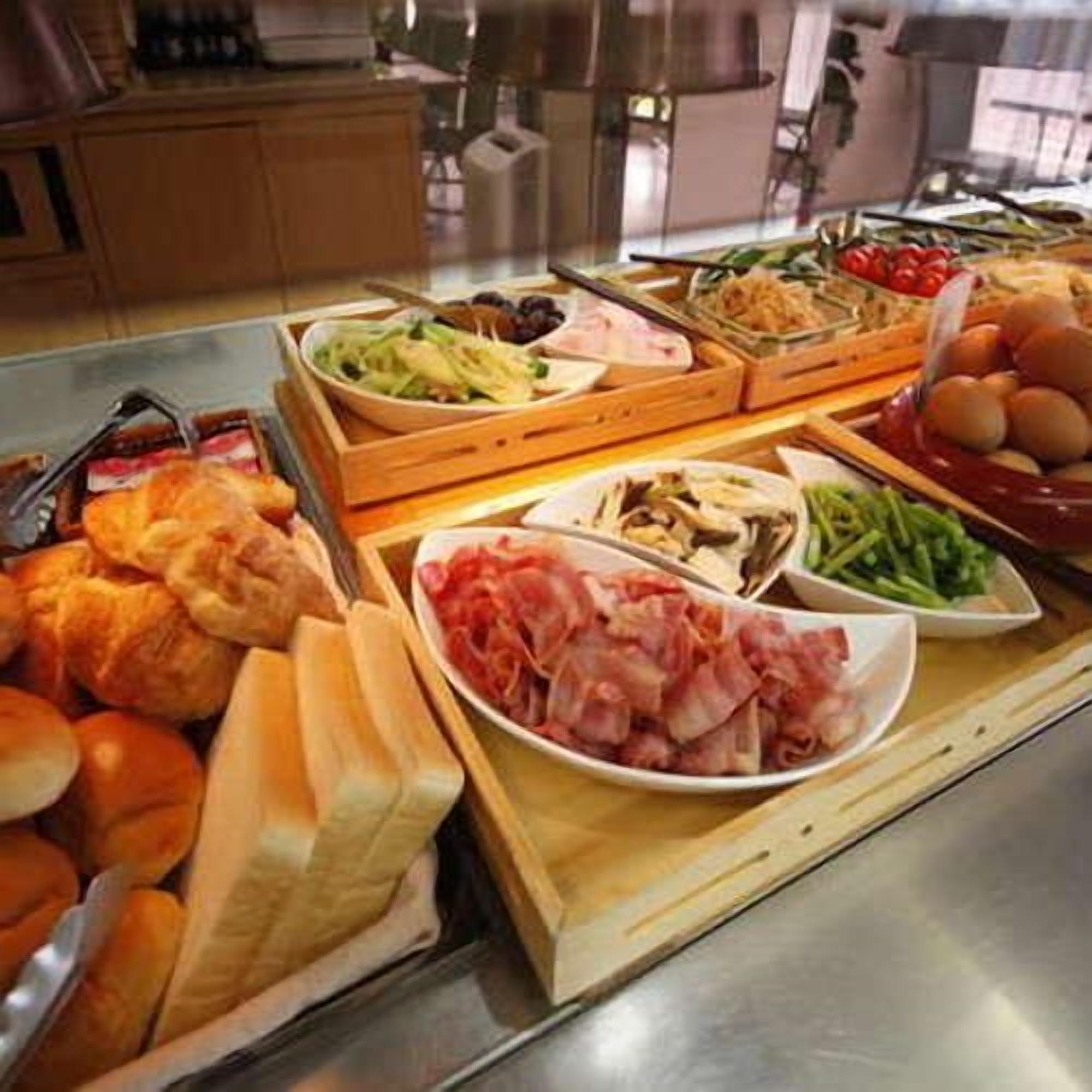 Een buffet met diverse soorten eten, zoals vlees, groenten en brood.