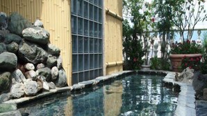 A clear pool with stone edges, surrounded by rocks and a wooden fence. - Hotel Taihei (Matsuyama)