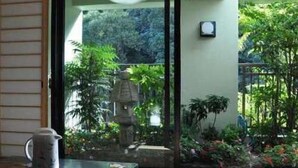 A traditional Japanese room with tatami flooring, a low table with a ceramic pitcher, and a view of a garden through a sliding door. - Hotel Taihei (Matsuyama)