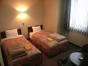 A hotel room with two single beds, a small table, and a chair. - Hotel Nakajima (Saku)