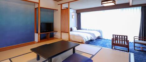Habitación de hotel con suelo de tatami, una cama, un televisor en un estante, un escritorio y una silla.