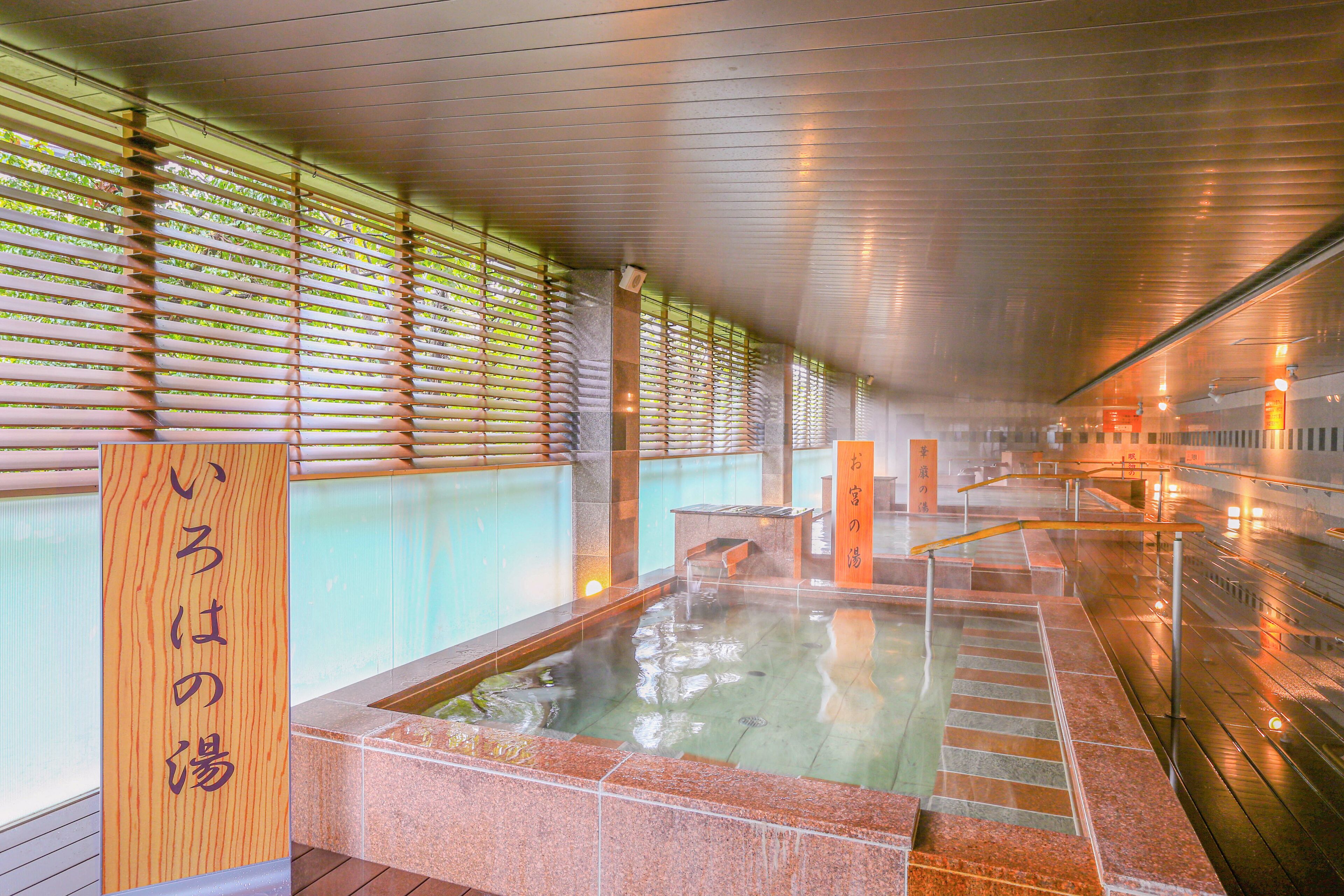 A traditional Japanese onsen with a wooden sign, stone steps, and a view of the interior.