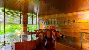 A traditional Japanese onsen with wooden interiors, stone benches, and a view of lush greenery outside. - Ooedo Onsen Monogatari Premium Kinugawa Kanko Hotel (Nikko)