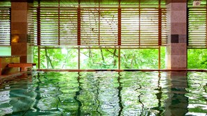 An indoor swimming pool with a view of lush greenery through large windows. - Ooedo Onsen Monogatari Premium Kinugawa Kanko Hotel (Nikko)