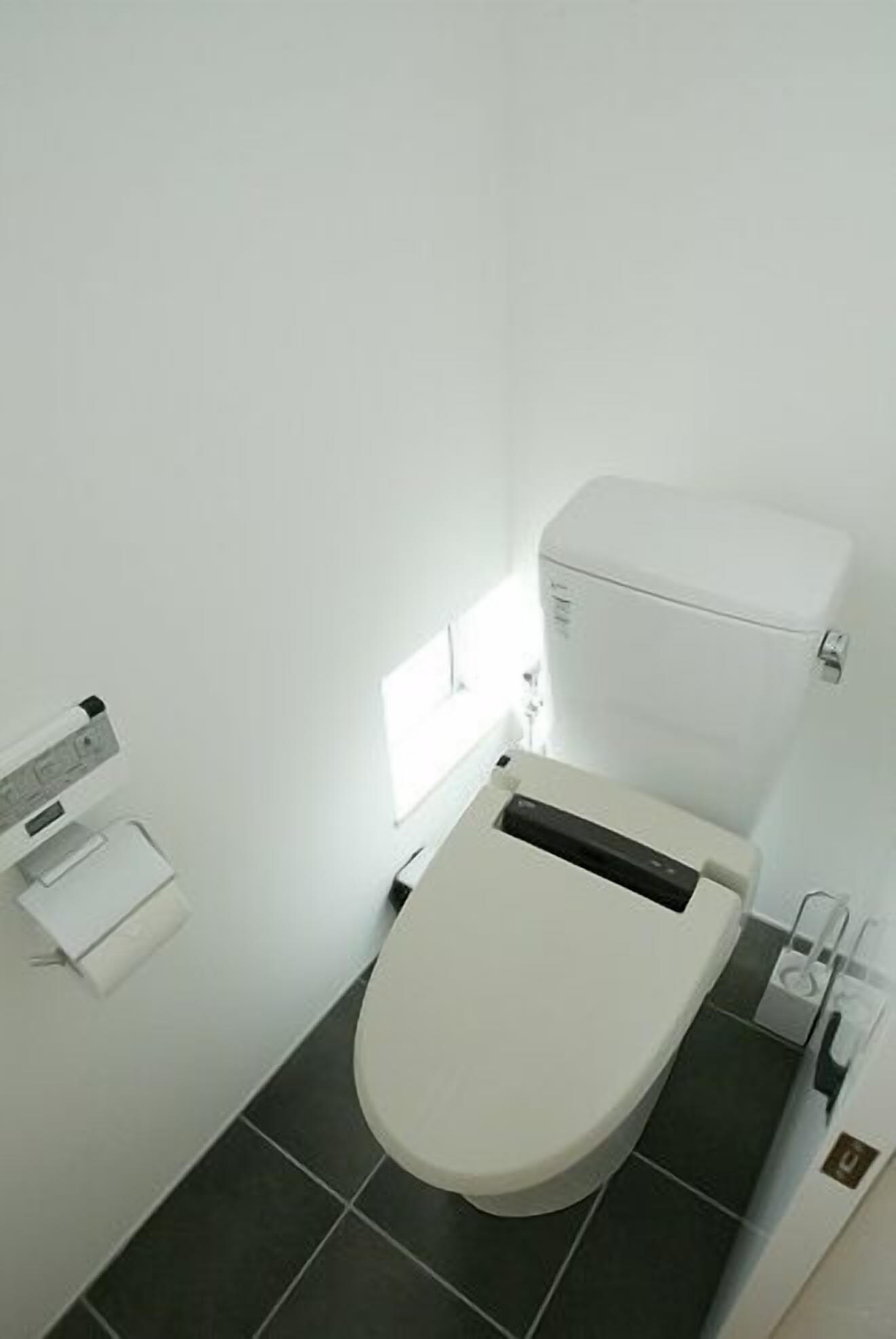 Ein kleines, modernes Badezimmer mit Toilette, Waschbecken und einem Fenster, das für natürliches Licht sorgt.