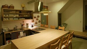 A modern kitchen with a central island, wooden chairs, a hanging light fixture, and a globe on the shelf. - Ohenroyado Tabibito no Yado Kaze no Kuguru (Zentsuji)