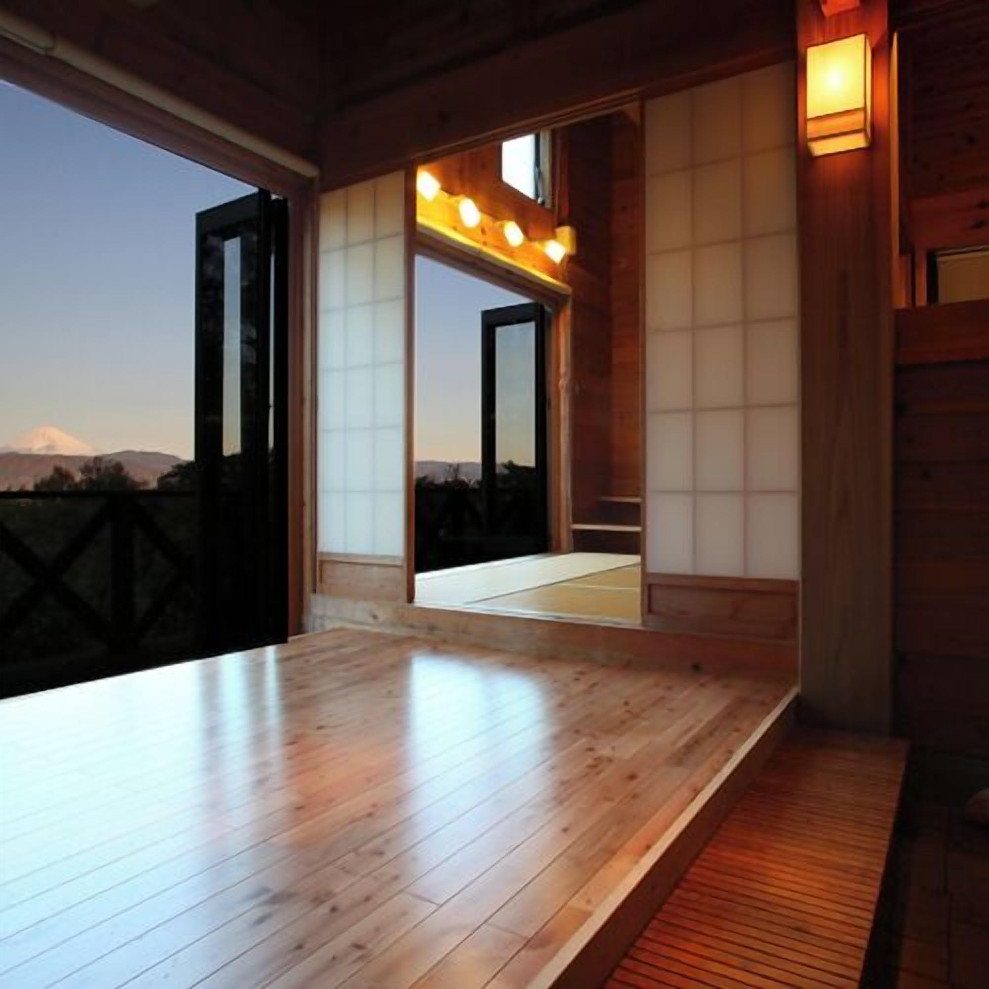 A wooden interior with a large table, sliding doors, and a view of a mountain.