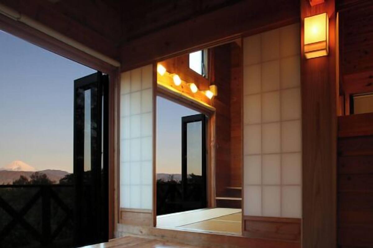 A wooden interior with a large table, sliding doors, and a view of a mountain.