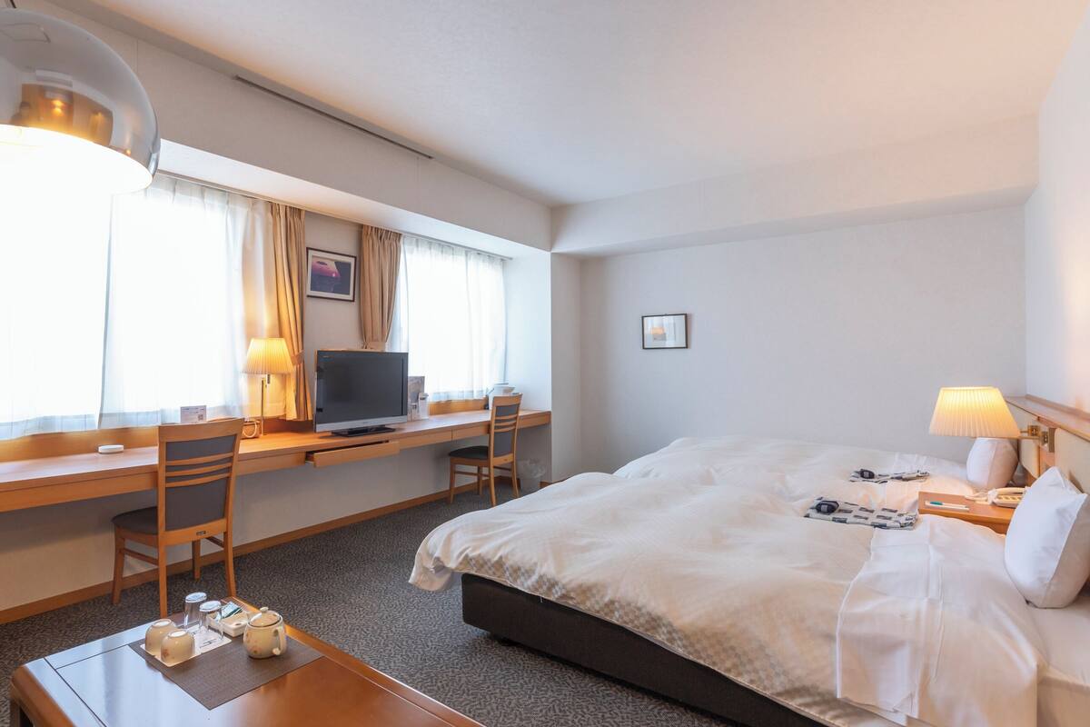 Une chambre d’hôtel équipée d’un lit, d’un bureau, d’une chaise, d’une télévision, d’une lampe et d’un fauteuil massant.
