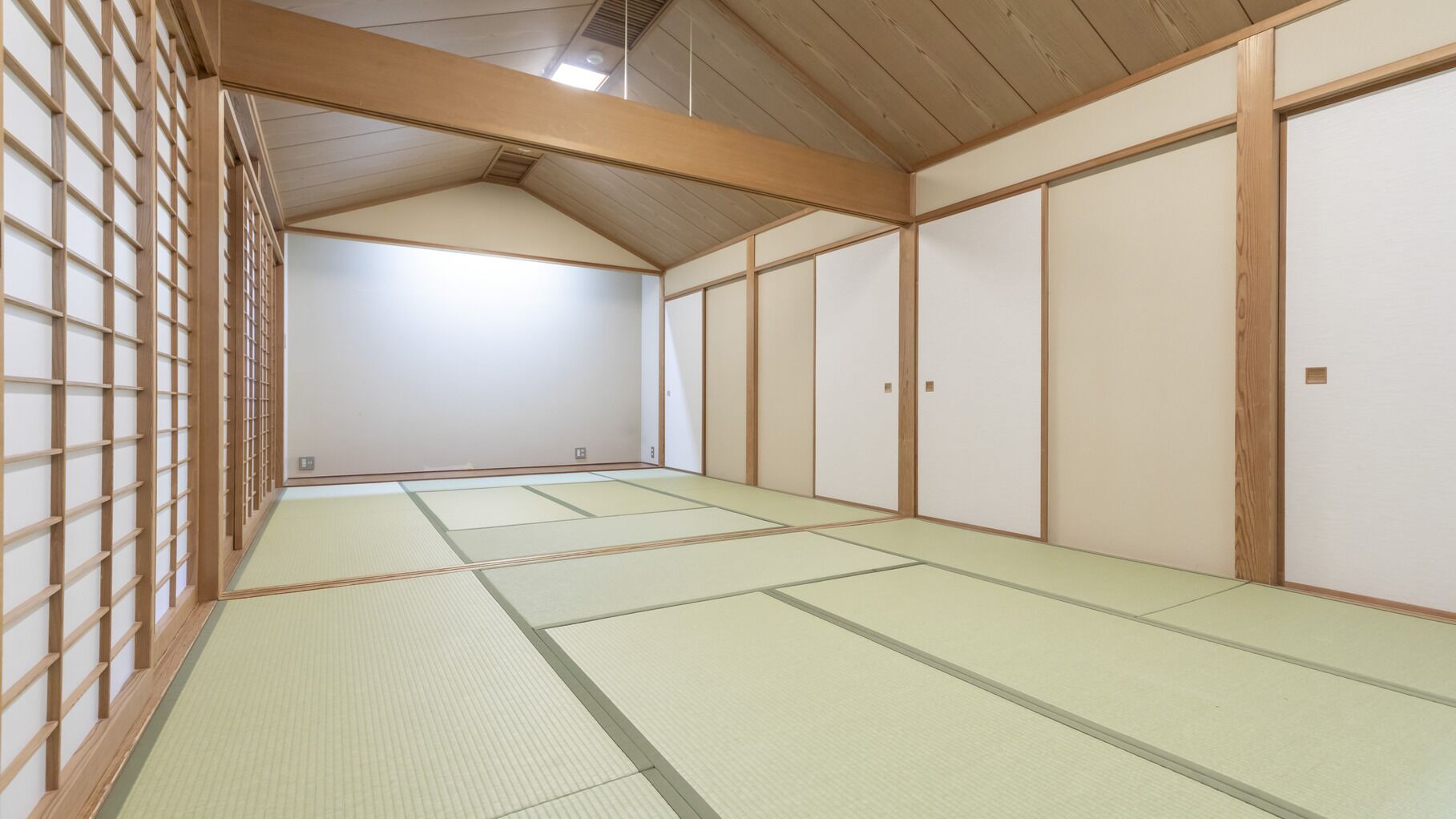 Una habitación japonesa tradicional con suelo de tatami, puertas correderas y vigas de madera.