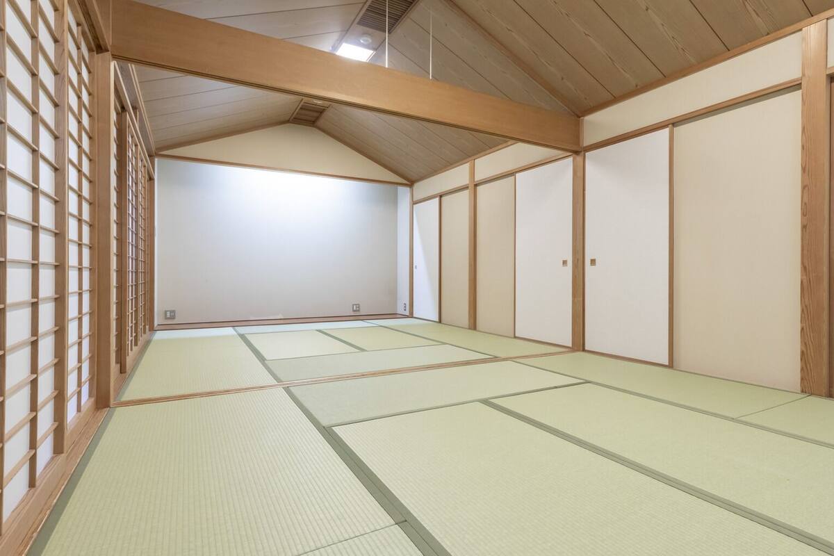 Une pièce de style japonais traditionnel, avec un sol recouvert de tatamis, des portes coulissantes et des poutres en bois.