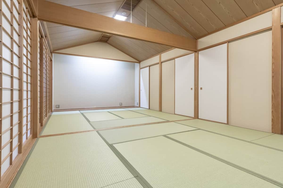 A traditional Japanese room with tatami flooring, sliding doors, and wooden beams.