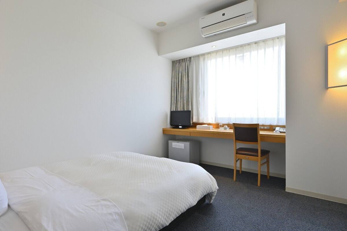 Une chambre d’hôtel équipée d’un lit, d’un bureau, d’une chaise et d’un appareil de climatisation.