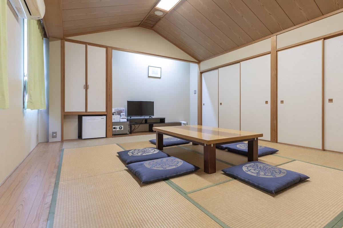 A traditional Japanese room with tatami flooring, a low wooden table, and shoji screens.