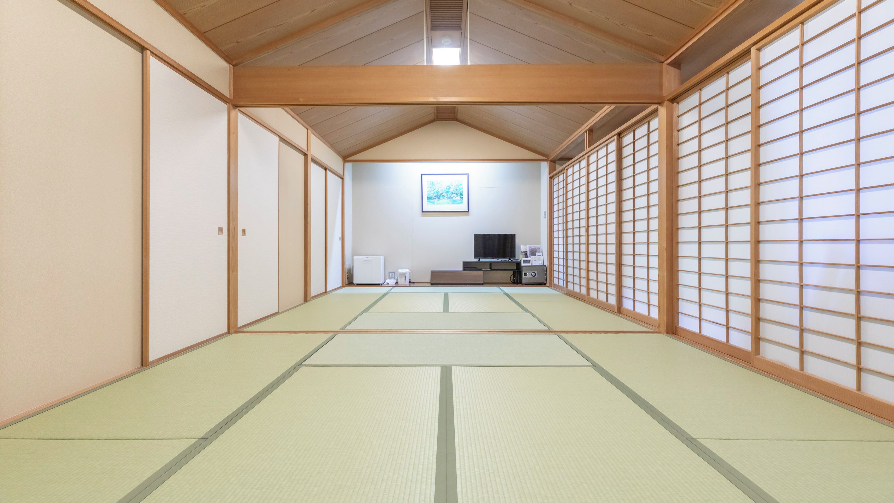A traditional Japanese room with tatami flooring, sliding doors, and a television.