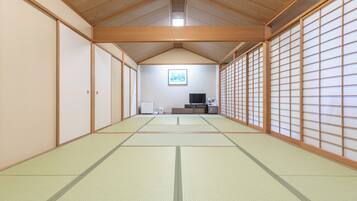 A traditional Japanese room with tatami flooring, sliding doors, and a television.