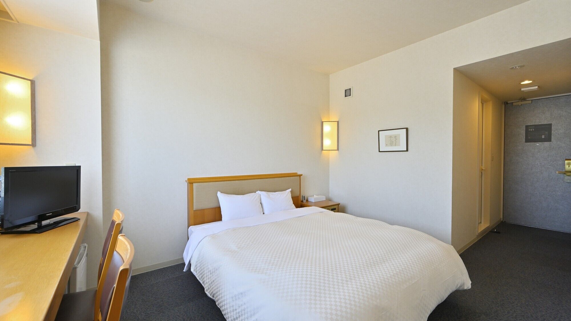 Una habitación de hotel con cama, televisión, escritorio y silla.