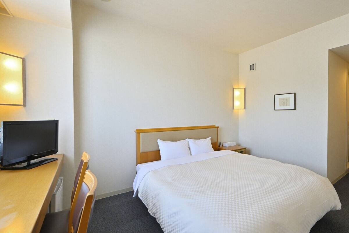 Une chambre d’hôtel équipée d’un lit, d’une télévision, d’un bureau et d’une chaise.