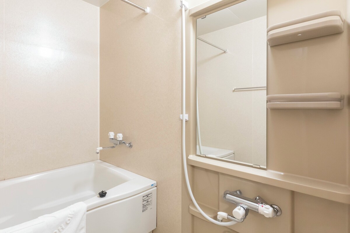 A bathroom with a bathtub, a shower, and a mirror.
