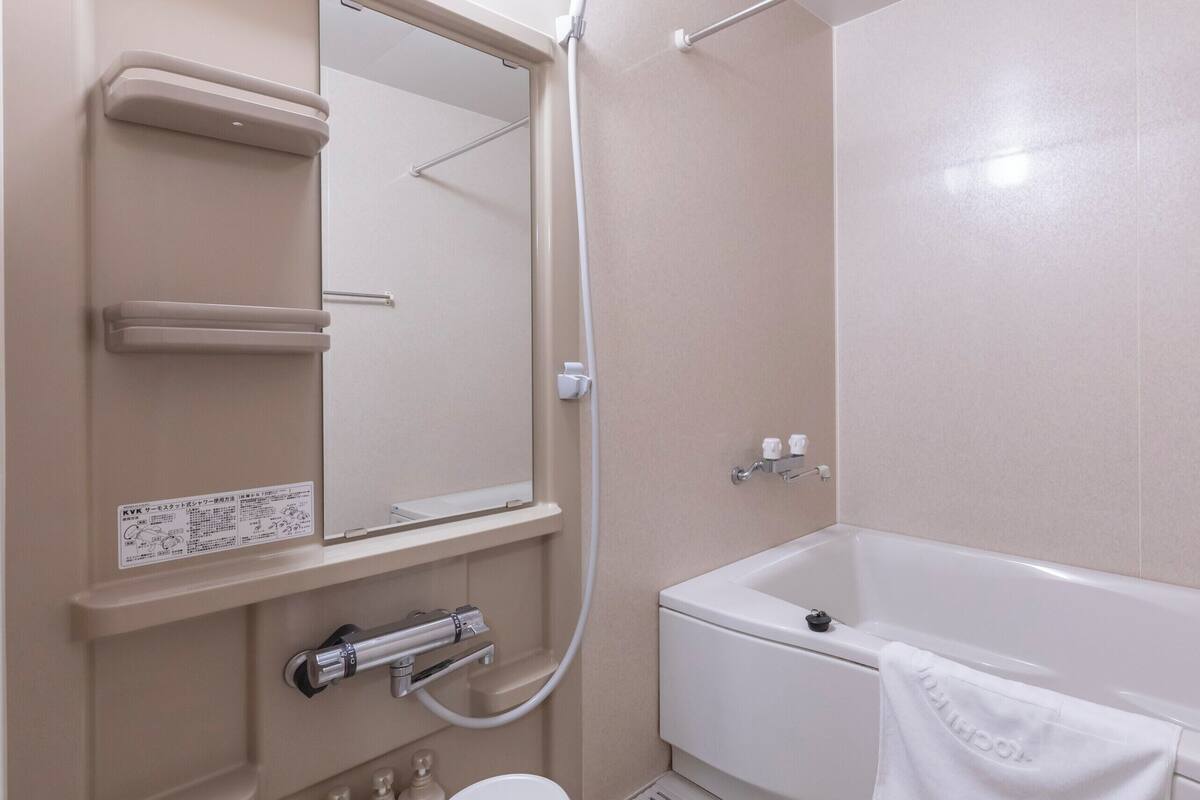 Une salle de bain équipée d’une baignoire, de toilettes, d’un lavabo, d’un miroir et d’un porte-serviettes.