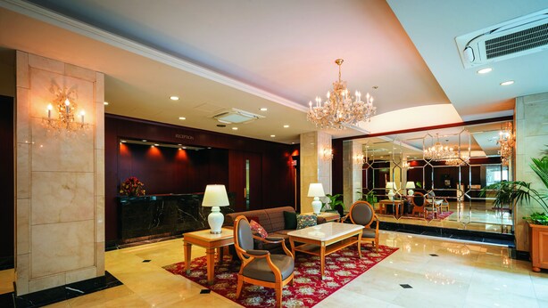 A spacious lobby with a reception desk, seating area, and a large mirror reflecting the interior. - Hotel Patio Dogo (Matsuyama)