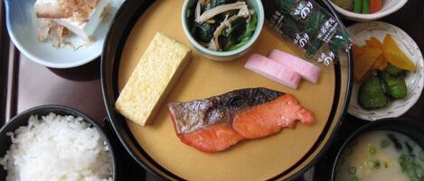 Un repas japonais traditionnel composé de riz, de saumon, de tofu et de divers légumes.
