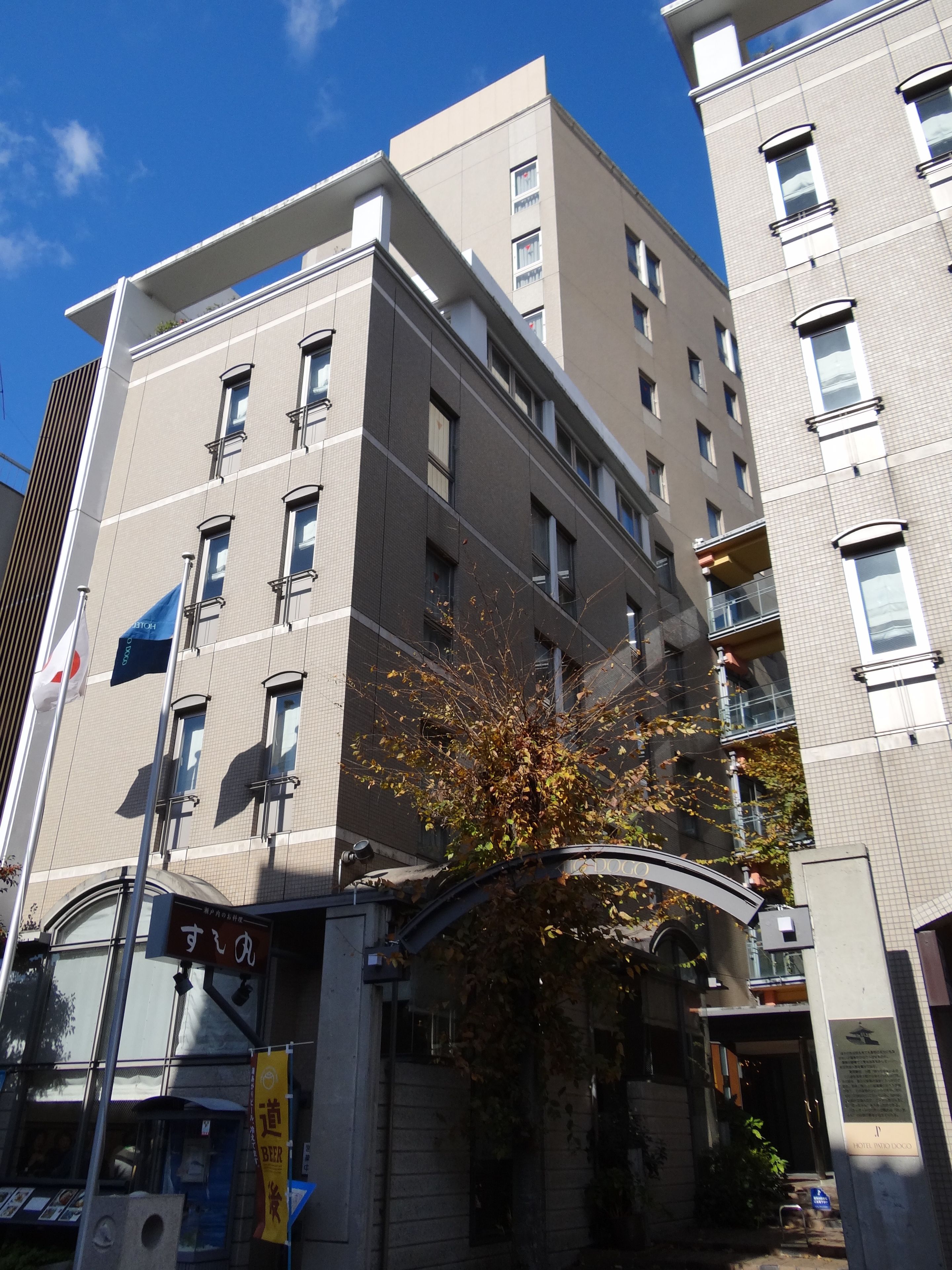 A multi-story hotel with a modern architectural design, featuring a prominent entrance with a curved awning and a sign indicating a beer garden.