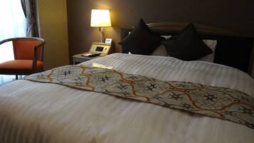 Una habitación de hotel con una cama bien hecha, una mesita de noche con una lámpara y una silla.