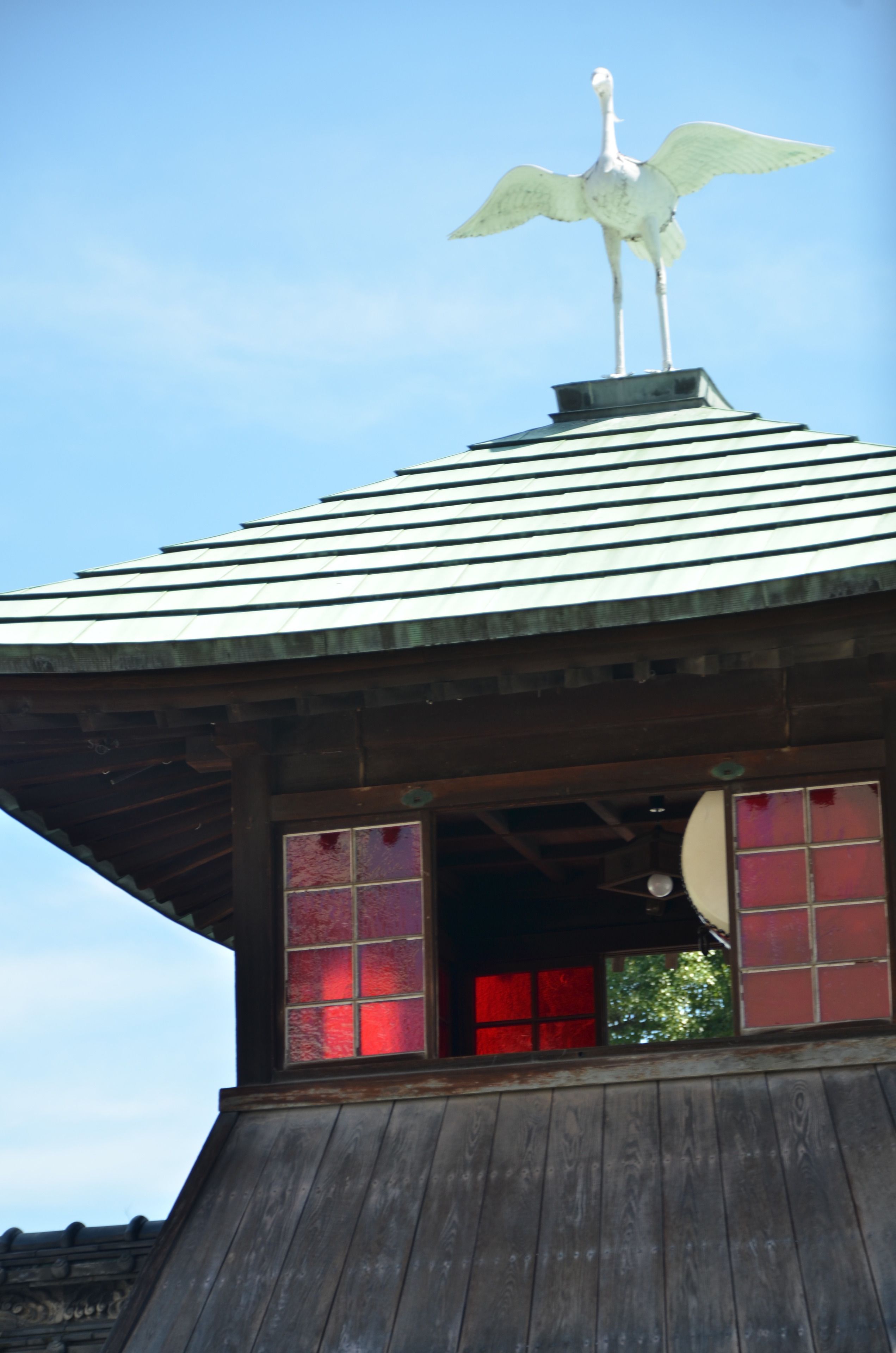 A building with a sloped roof and a bird sculpture on top.