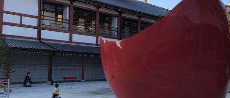 A traditional building with a large red sculpture in the foreground.