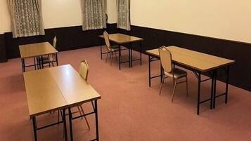 A conference room with four tables and chairs, a carpeted floor, and curtains on the windows.