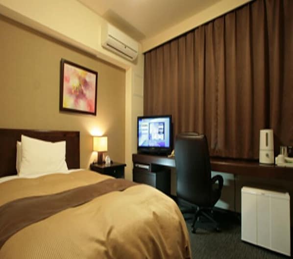 A hotel room with a bed, a desk with a computer, a chair, a lamp, and an air conditioning unit. - Hotel Sealuck Pal Utsunomiya (Utsunomiya)