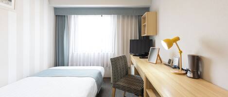 Une chambre d’hôtel équipée d’un lit, d’un bureau avec un ordinateur, d’une chaise, d’une télévision et d’une machine à café.