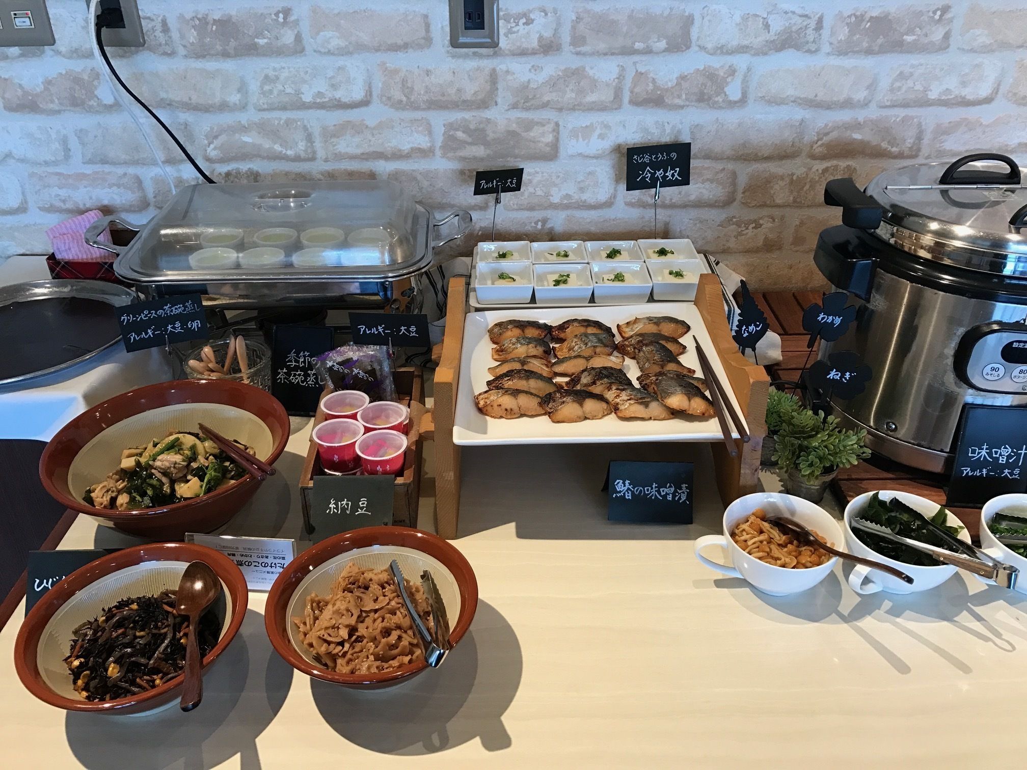 A buffet with various dishes, including fish, vegetables, and a hot pot.