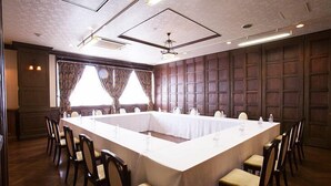 Un salón de conferencias con una mesa larga, sillas y cortinas.