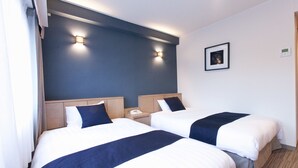Habitación de hotel con dos camas, una mesita de noche con teléfono y dos lámparas de pared.