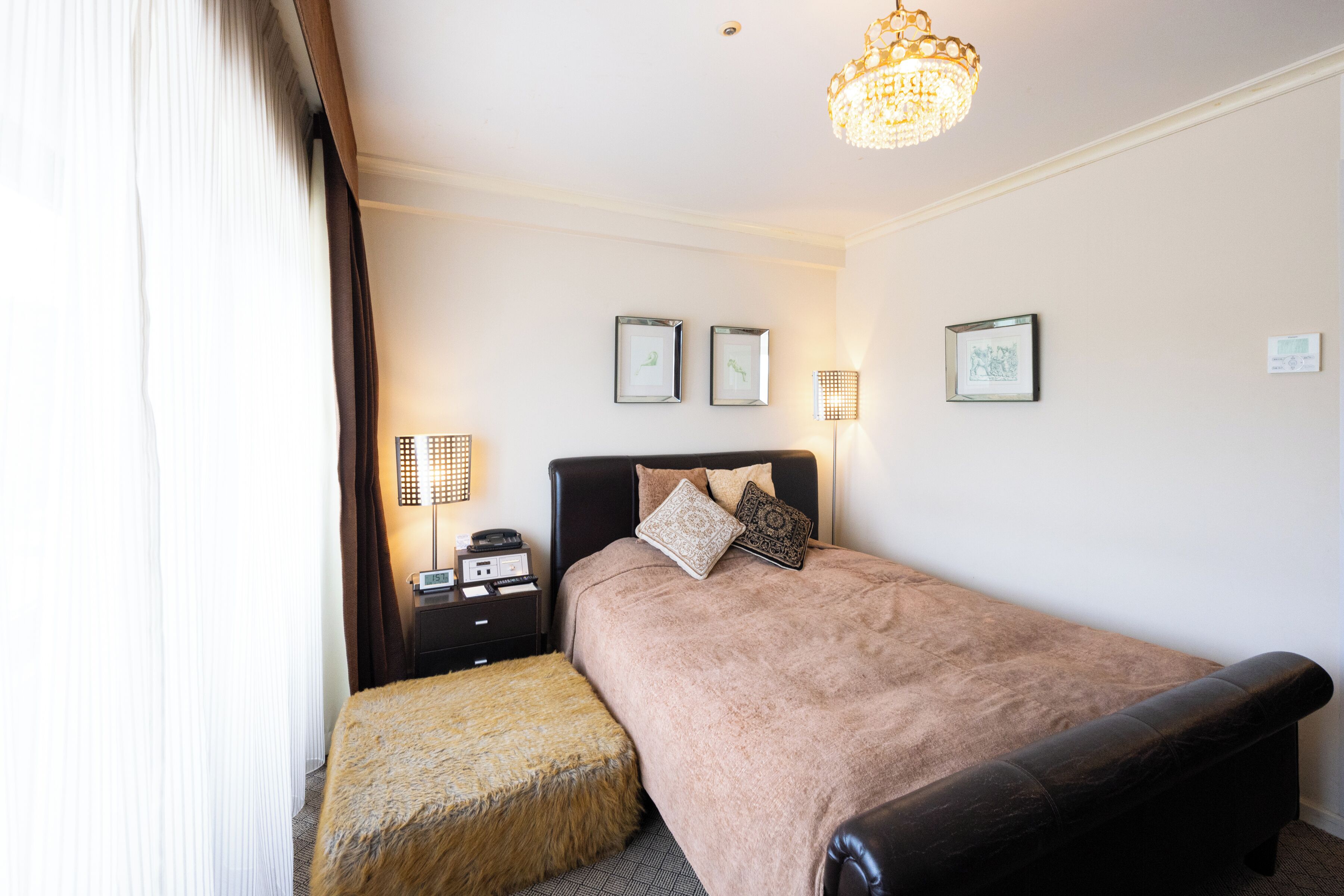 A bedroom with a bed, bedside tables, a lamp, and framed pictures on the wall.