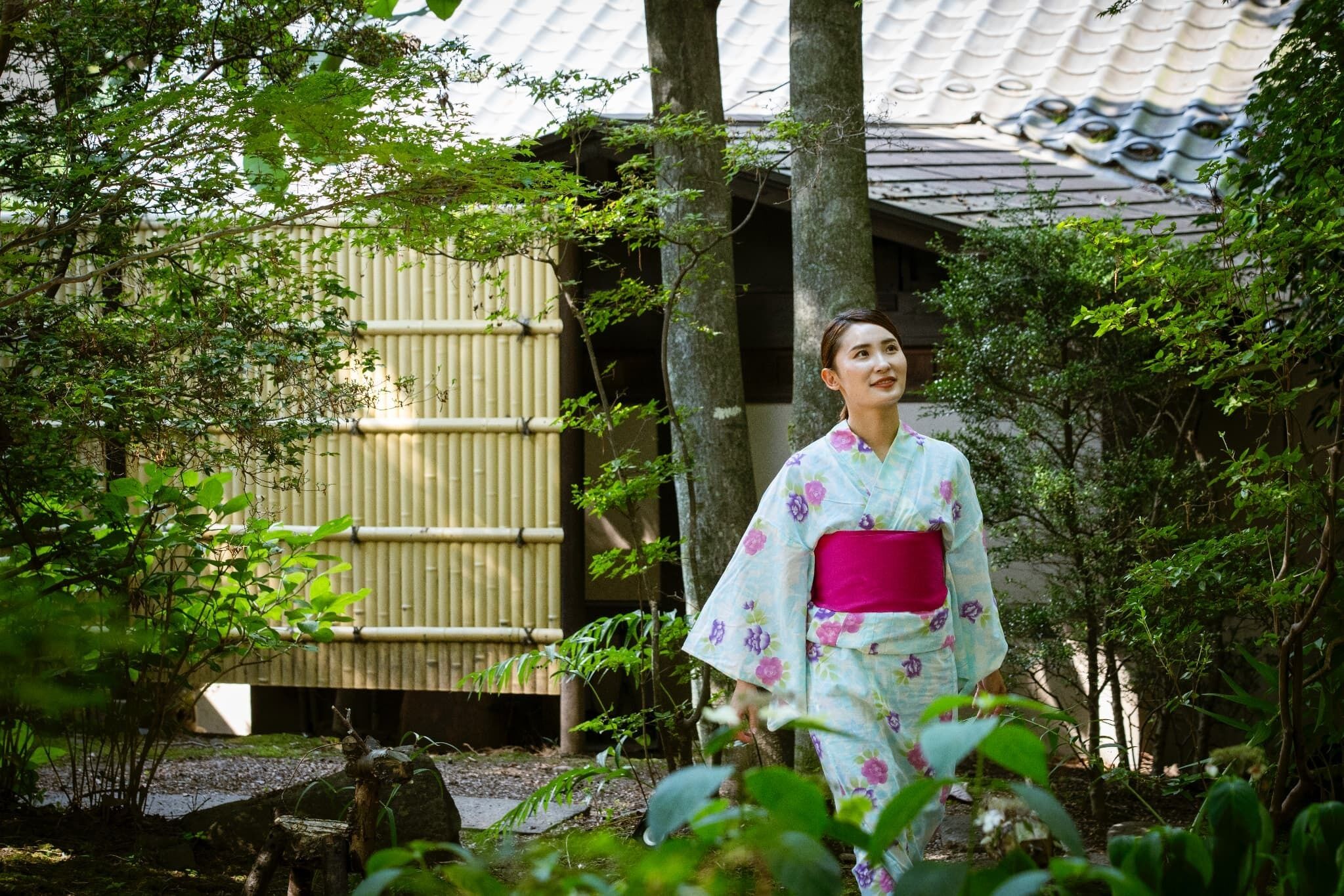 A traditional Japanese building with a tiled roof and a bamboo fence.