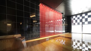A modern interior with a wooden reception desk, a red wall with reflective tiles, and a checkered floor pattern. - Hoshino Resorts Bandaisan Onsen Hotel (Bandai)