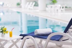 A poolside area with a lounge chair, a towel, a glass of orange juice, and a small plant. - Hoshino Resorts Bandaisan Onsen Hotel (Bandai)