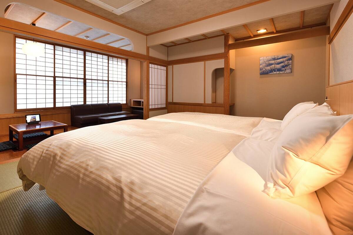 A hotel room with a large bed, a desk, a chair, and a window with a view.