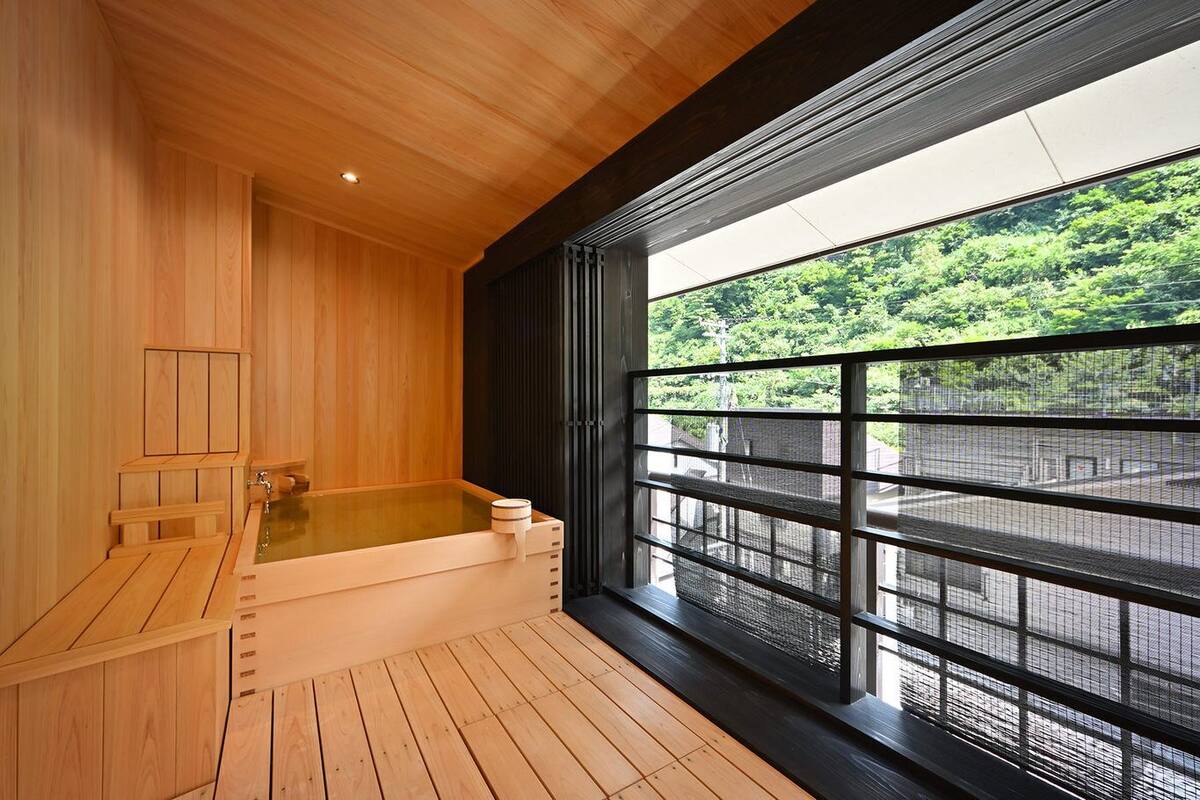 A wooden sauna room with a large window overlooking a forested area.