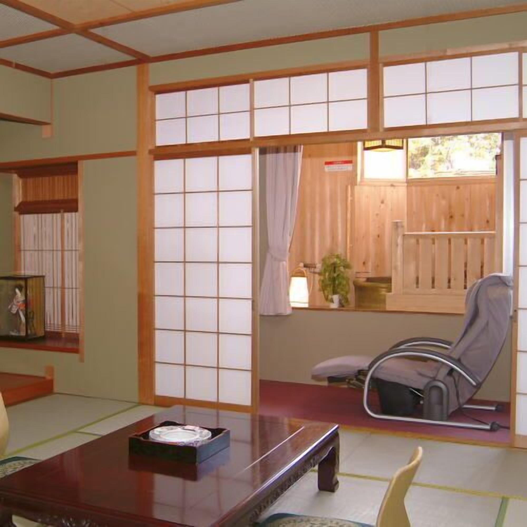 A traditional Japanese room with tatami flooring, a low table, a chair, and sliding doors.