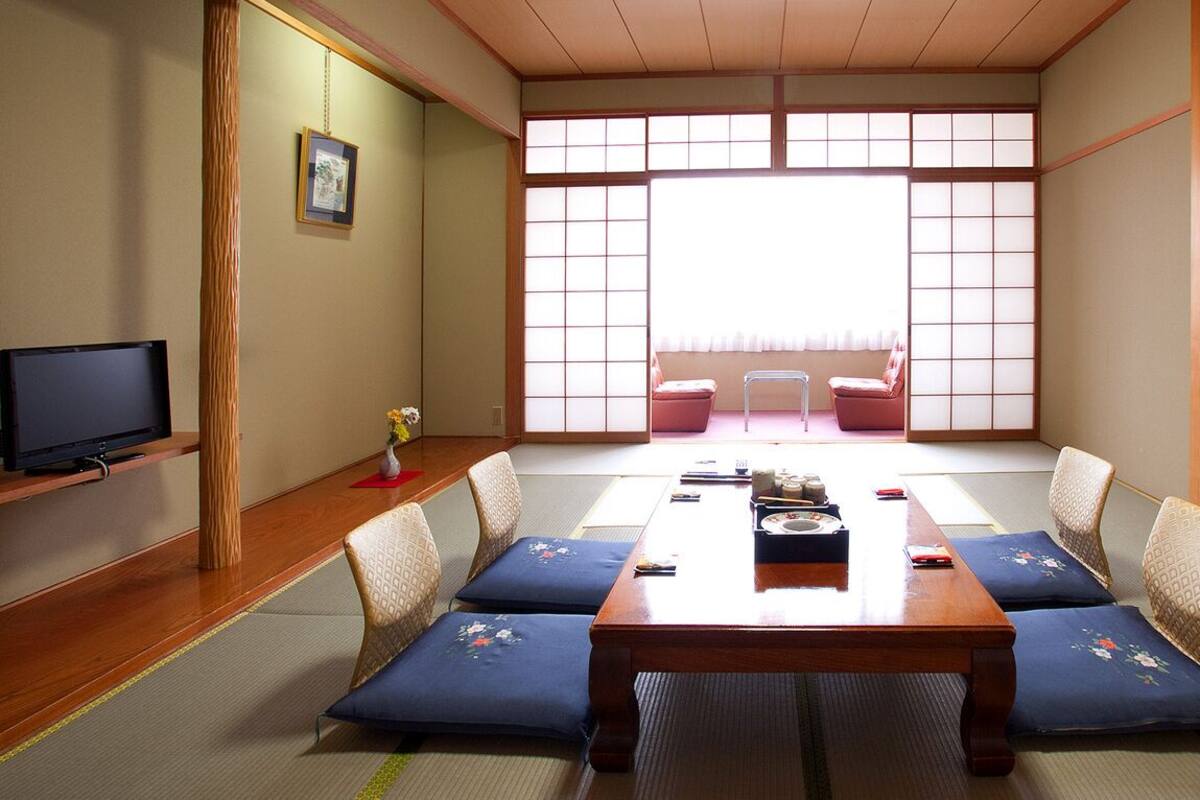 Una habitación japonesa tradicional con suelo de tatami, una mesa de madera baja y puertas correderas shoji.