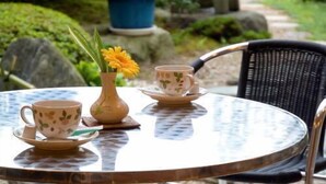 A round table with a tea set, a vase with a yellow flower, and a stone lantern in a garden setting. - Ashihara Onsen Hakuwaso (Awara)