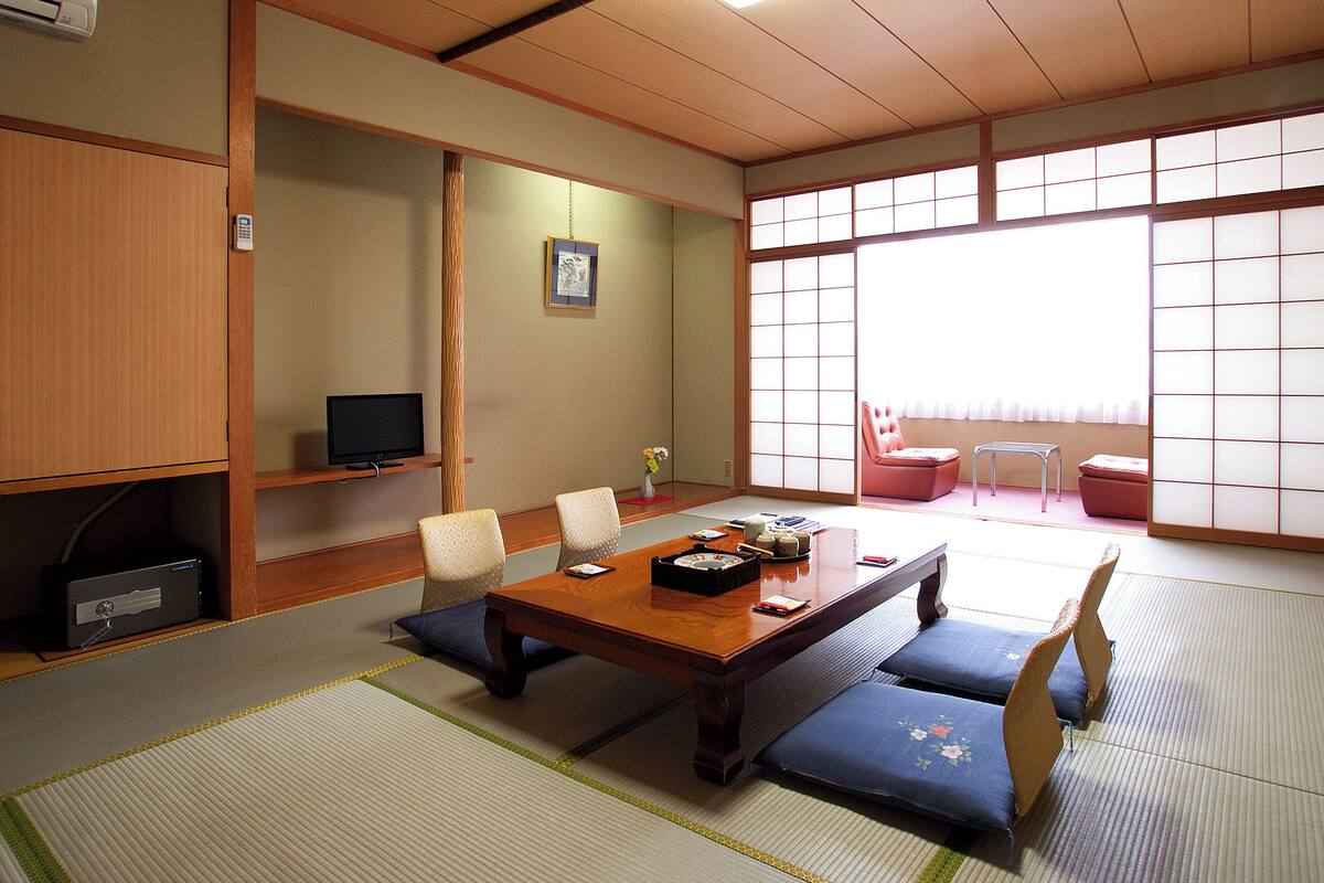 Una habitación tradicional japonesa con suelo de tatami, una mesa baja y puertas correderas shoji.