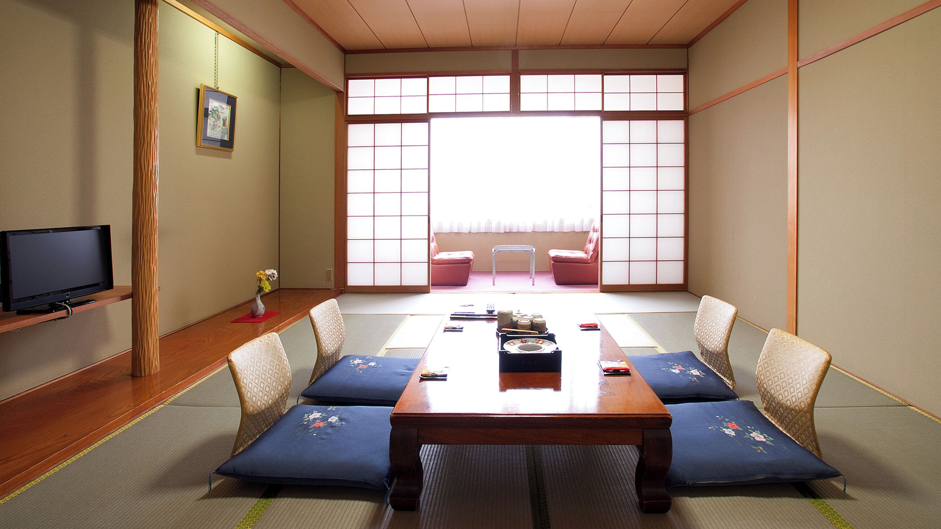 A traditional Japanese room with tatami flooring, a low table, cushions, a television, and sliding doors.