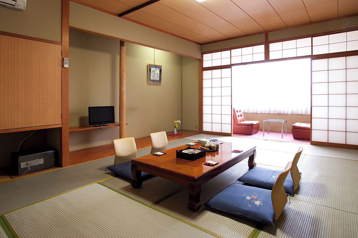 A traditional Japanese room with tatami flooring, a low table, and shoji screens.